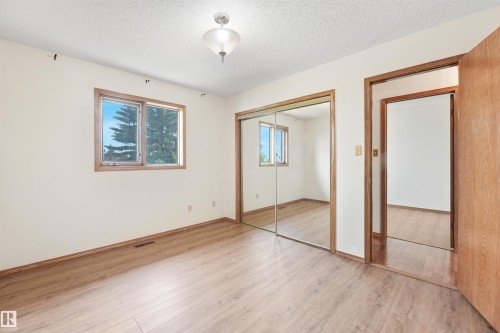 Expansive room featuring wood-finish flooring, a large window with wood trim, and a ceiling-mounted light fixture - 8008 158 Avenue Nw, Edmonton, AB - Indoor Photo Showing Other Room