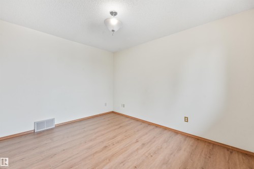 Room featuring wood-finish flooring, light-toned walls, and a ceiling-mounted light fixture - 8008 158 Avenue Nw, Edmonton, AB - Indoor Photo Showing Other Room
