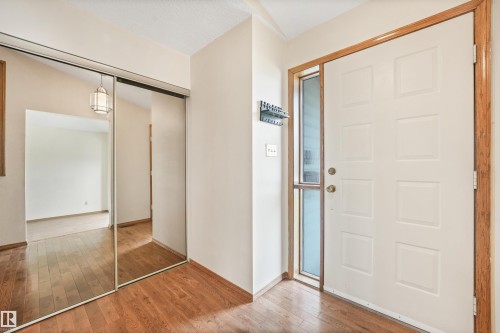 Entryway featuring wood-finish flooring, a paneled entry door with sidelight, and a mirrored sliding closet door - 8008 158 Avenue Nw, Edmonton, AB - Indoor Photo Showing Other Room
