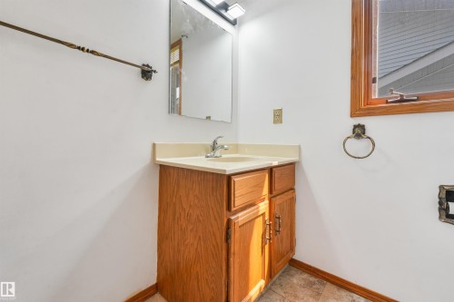 Bathroom vanity with wood-finish cabinetry, a light-toned countertop, and an integrated sink with a chrome faucet - 8008 158 Avenue Nw, Edmonton, AB - Indoor Photo Showing Bathroom