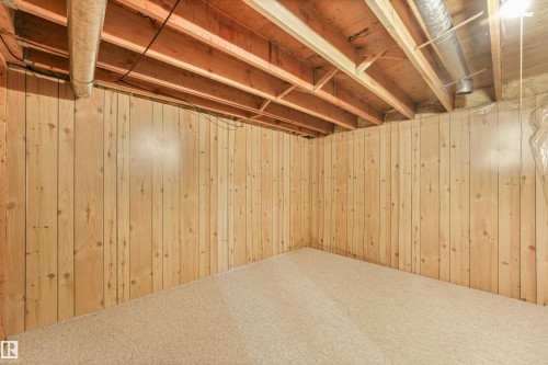 Finished basement space with wood-paneled walls and neutral carpeting - 8008 158 Avenue Nw, Edmonton, AB - Indoor