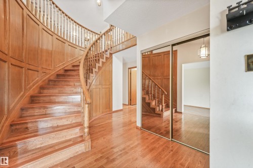 Sweeping wooden staircase with a paneled banister, hardwood flooring, mirrored closet doors, and recessed lighting - 8008 158 Avenue Nw, Edmonton, AB - Indoor Photo Showing Other Room
