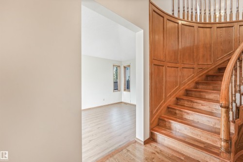 Curved wooden staircase featuring paneled wainscoting and turned balusters - 8008 158 Avenue Nw, Edmonton, AB - Indoor Photo Showing Other Room