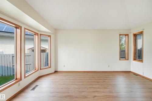 Bright interior space featuring a curved bay window with wood-frame windows and wood-finish flooring - 8008 158 Avenue Nw, Edmonton, AB - Indoor Photo Showing Other Room