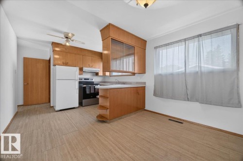 Kitchen featuring wood-finish cabinetry, stainless steel range, and ceiling fan - 6104 92 Avenue Nw, Edmonton, AB 