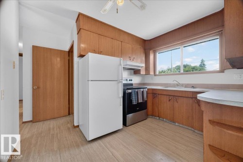 Wood-finish flooring with full kitchen cabinetry and a ceiling fan - 6104 92 Avenue Nw, Edmonton, AB 