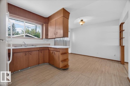 Kitchen featuring wood cabinetry, a stainless steel sink, and light-toned countertops - 6104 92 Avenue Nw, Edmonton, AB 