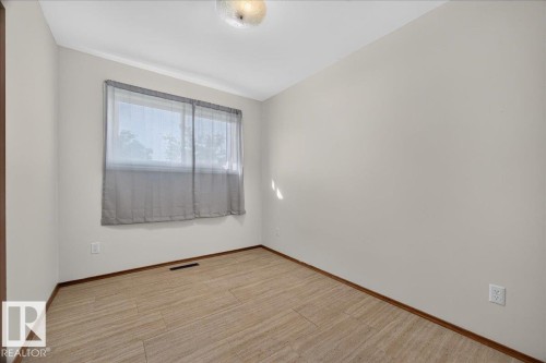 Neutral tone wall paint, wood-finish flooring, baseboard trim, and a ceiling-mounted light fixture - 6104 92 Avenue Nw, Edmonton, AB 