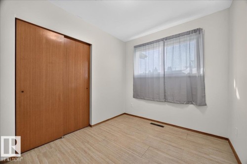 Wood-finish flooring with baseboard trim, neutral wall color, and a window with natural light - 6104 92 Avenue Nw, Edmonton, AB 