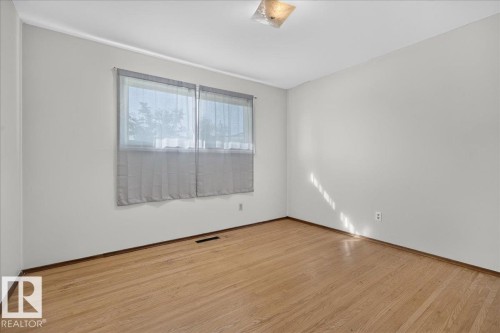Hardwood flooring, light gray walls, window with blinds, and a ceiling-mounted light fixture - 6104 92 Avenue Nw, Edmonton, AB 