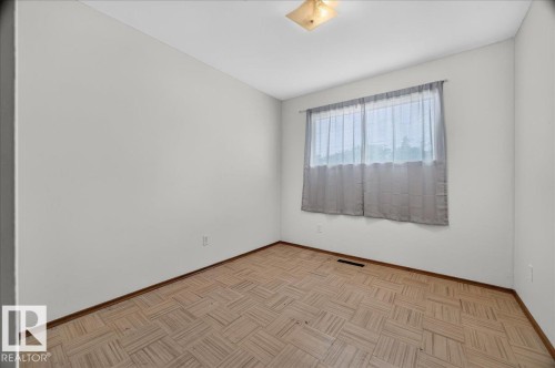Neutral wall tones with wood-finish parquet flooring and a flush-mount ceiling light fixture - 6104 92 Avenue Nw, Edmonton, AB 