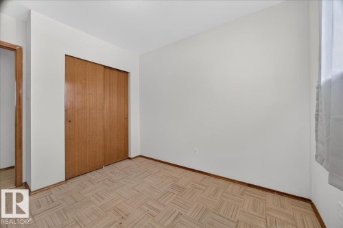 Neutral wall paint, wood-finish flooring, sliding closet doors, and a window with sheer covering - 6104 92 Avenue Nw, Edmonton, AB 
