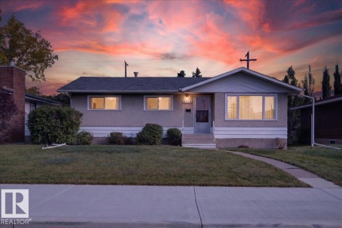Single-story residence featuring a gabled entryway, stucco exterior, front yard with mature landscaping, and a concrete walkway - 6104 92 Avenue Nw, Edmonton, AB 