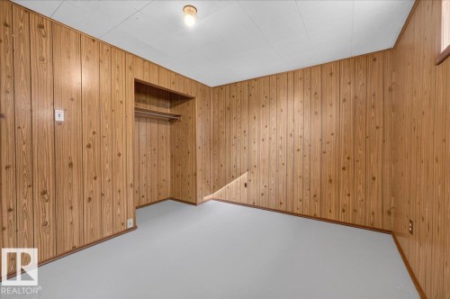 Wood-paneled walls with built-in shelving, a garment rod, and light-toned flooring - 6104 92 Avenue Nw, Edmonton, AB 