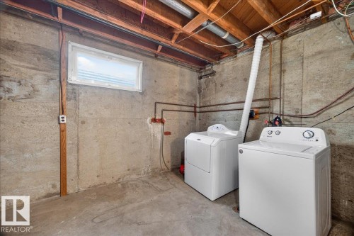 Basement laundry area featuring a window, exposed ceiling joists, and concrete flooring - 6104 92 Avenue Nw, Edmonton, AB 