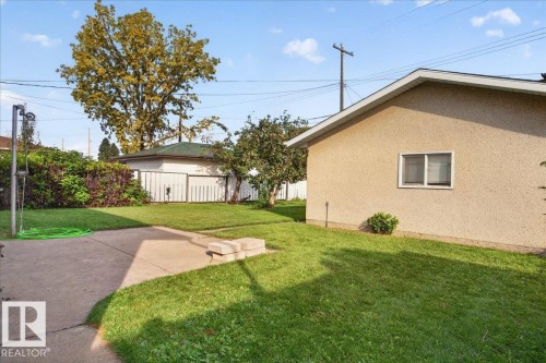 Expansive backyard featuring a concrete patio, a manicured lawn, mature trees, and privacy fencing - 6104 92 Avenue Nw, Edmonton, AB 