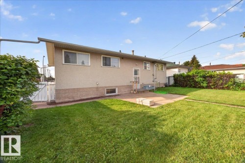Expansive backyard with a concrete patio, grassy lawn, and mature perimeter landscaping - 6104 92 Avenue Nw, Edmonton, AB 