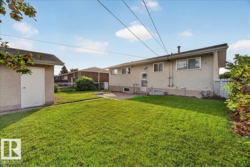 Expansive rear yard featuring a concrete patio, mature lawn, and a detached storage shed - 6104 92 Avenue Nw, Edmonton, AB 