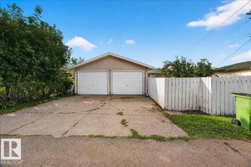 Detached garage featuring two garage doors, stucco exterior, and a gabled roofline - 6104 92 Avenue Nw, Edmonton, AB 
