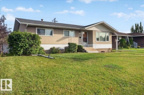 Stucco exterior with a peaked roofline, front entry steps with metal railings, and a large bay window - 6104 92 Avenue Nw, Edmonton, AB 