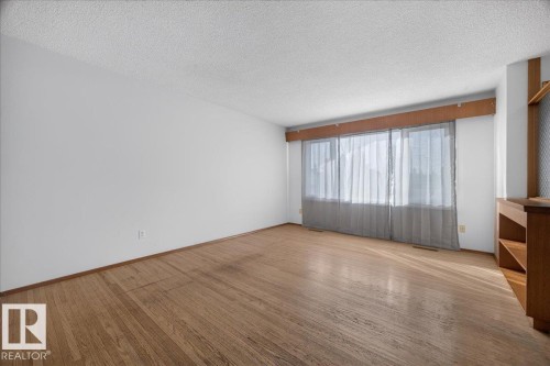 Expansive room featuring hardwood flooring, abundant natural light, and built-in shelving - 6104 92 Avenue Nw, Edmonton, AB 