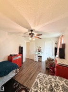 Wood-finish flooring throughout, ceiling fan with integrated lighting, and multiple paneled doors - 