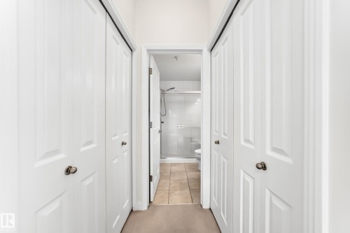 Hallway featuring bi-fold panel doors, neutral wall paint, and carpet flooring - #307 1003 Gault Bv Nw, Edmonton, AB - Indoor Photo Showing Other Room