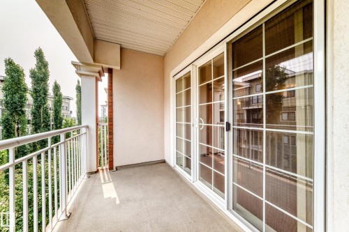 Private balcony featuring a concrete floor, white metal railing, and a brick-faced accent column - #307 1003 Gault Bv Nw, Edmonton, AB - Outdoor With Exterior