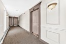 Hallway featuring wainscoting, decorative wall sconces, patterned carpet flooring, and paneled doors with substantial trim - #307 1003 Gault Bv Nw, Edmonton, AB  - Indoor Photo Showing Other Room 
