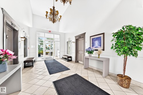 Bright common area featuring vaulted ceilings, a decorative chandelier, and tile flooring - #307 1003 Gault Bv Nw, Edmonton, AB - Indoor Photo Showing Other Room