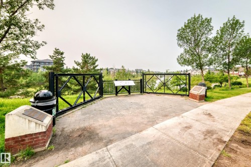 Paved patio space featuring a decorative metal fence and informational display - #307 1003 Gault Bv Nw, Edmonton, AB - Outdoor