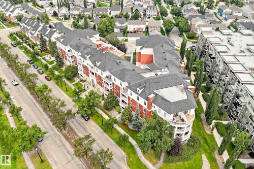 Multi-story building featuring red brick and white siding, individual balconies, dark shingle roofing, and established landscaping - #307 1003 Gault Bv Nw, Edmonton, AB - Outdoor With View