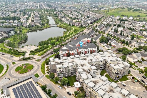 Aerial perspective showcasing residential developments, a central roundabout, and a prominent solar panel array - #307 1003 Gault Bv Nw, Edmonton, AB - Outdoor With Body Of Water With View