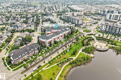 Aerial perspective showcasing a residential area with diverse architectural styles, including multi-story townhomes and modern apartment buildings - #307 1003 Gault Bv Nw, Edmonton, AB - Outdoor With Body Of Water With View