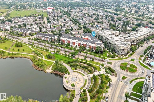 Aerial perspective showcasing a multi-story residential building with red brick and white accents, surrounded by a landscaped urban environment - #307 1003 Gault Bv Nw, Edmonton, AB - Outdoor With Body Of Water With View