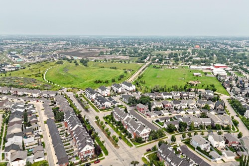 Aerial perspective showcasing a residential community with diverse housing styles, including detached homes and townhomes - #307 1003 Gault Bv Nw, Edmonton, AB - Outdoor With View