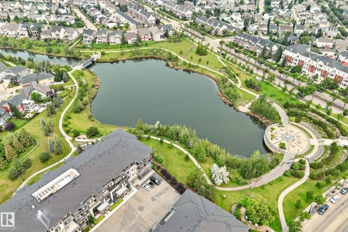 Aerial perspective showcasing a residential area featuring a central pond - #307 1003 Gault Bv Nw, Edmonton, AB - Outdoor With Body Of Water With View