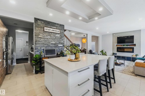 Kitchen island with light-toned countertop, integrated cabinetry, and bar seating - 7 Etoile Cres, St. Albert, AB 