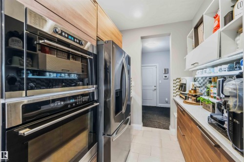 Stainless steel double oven, integrated refrigerator, wood-finish cabinetry, white countertops, and recessed lighting - 7 Etoile Cres, St. Albert, AB 