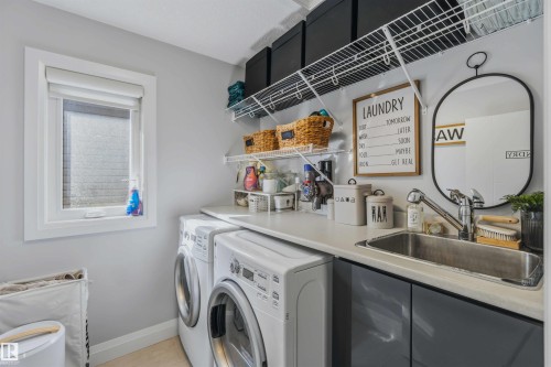Laundry area featuring a built-in sink, white wire shelving, dark gray cabinetry, and a window - 7 Etoile Cres, St. Albert, AB 