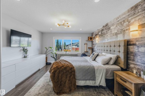 Accent wall featuring wood-finish paneling, contemporary ceiling light fixture, wood-finish flooring, recessed lighting, and a large window - 7 Etoile Cres, St. Albert, AB 