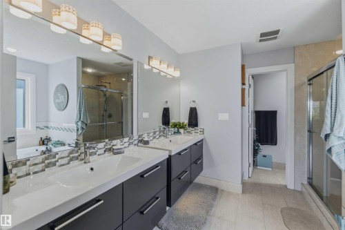 Dual vanity with integrated sinks, contemporary cabinetry, full-width mirrors, and a glass-enclosed shower - 7 Etoile Cres, St. Albert, AB 