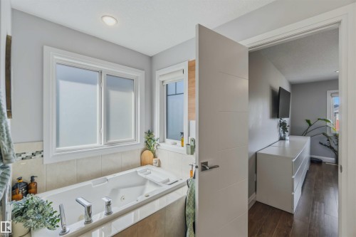 Built-in jetted tub with chrome fixtures, tiled surround, and multiple windows - 7 Etoile Cres, St. Albert, AB 