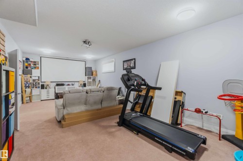 Spacious entertainment room featuring a large projection screen, recessed lighting, and light neutral-toned carpeting - 7 Etoile Cres, St. Albert, AB 
