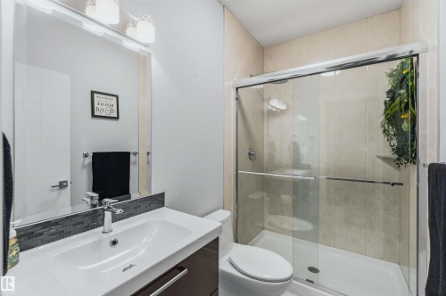 Contemporary vanity with integrated sink, mosaic tile backsplash, frameless mirror, and glass-enclosed shower with tile surround - 7 Etoile Cres, St. Albert, AB 