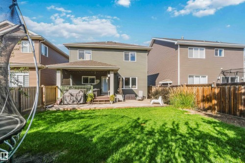 Expansive backyard with a manicured lawn, a wooden deck, and a covered patio area - 7 Etoile Cres, St. Albert, AB 