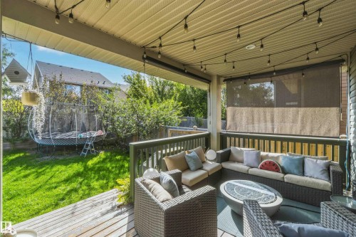Covered deck with wood flooring, dark wood railings, and built-in privacy screens - 7 Etoile Cres, St. Albert, AB 
