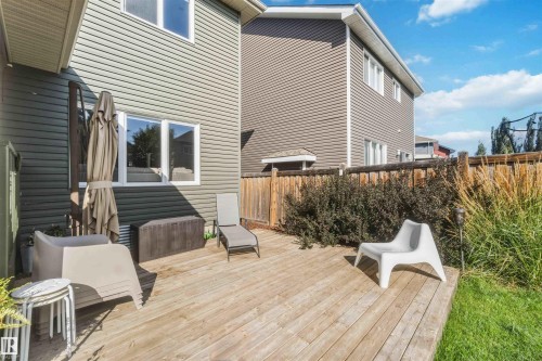 Expansive wooden deck with a wooden privacy fence, surrounded by mature shrubs and grass - 7 Etoile Cres, St. Albert, AB 