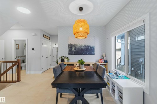 Bright dining area featuring a tiered pendant light, a large window, a built-in window bench with storage, and light-toned flooring - 7 Etoile Cres, St. Albert, AB 
