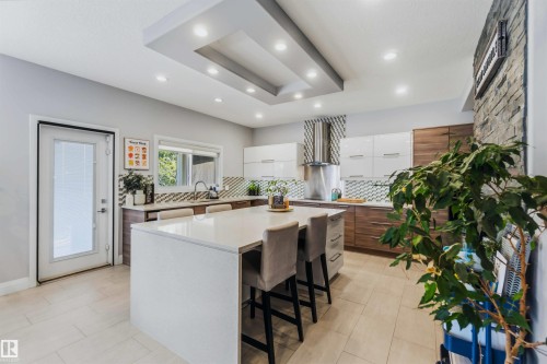 Kitchen featuring a large center island, recessed lighting, tile flooring, stone accent wall, and built-in cabinetry - 7 Etoile Cres, St. Albert, AB 